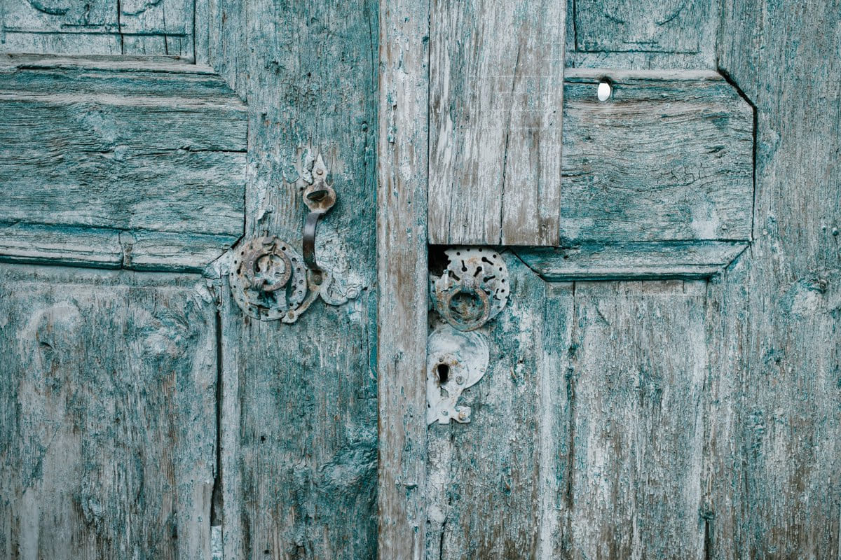 Shabby wooden blue doors with rusted locks.