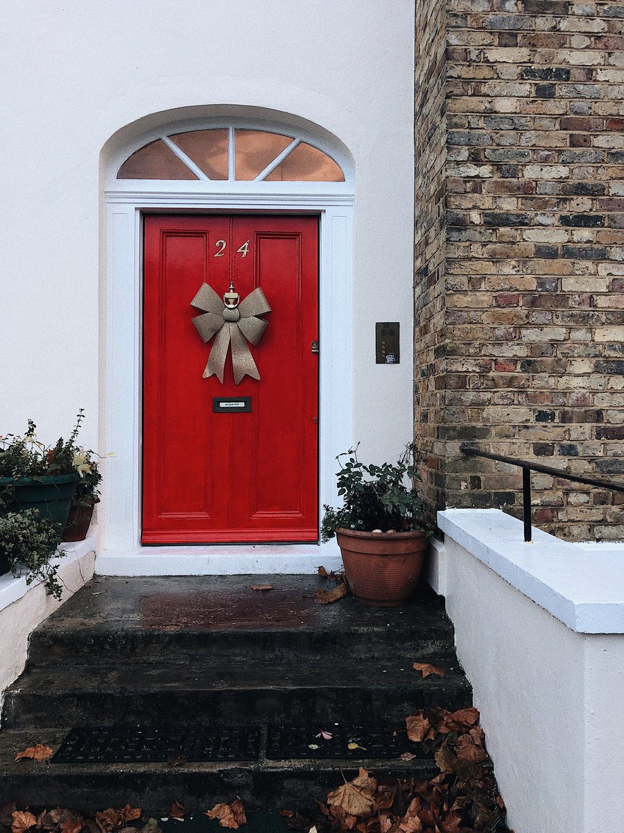 Steps leading up to a red wooden door with a bow on it.