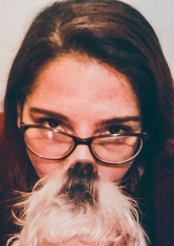 Selfie of a woman, and a dog looking up so the dog looks like it is her beard